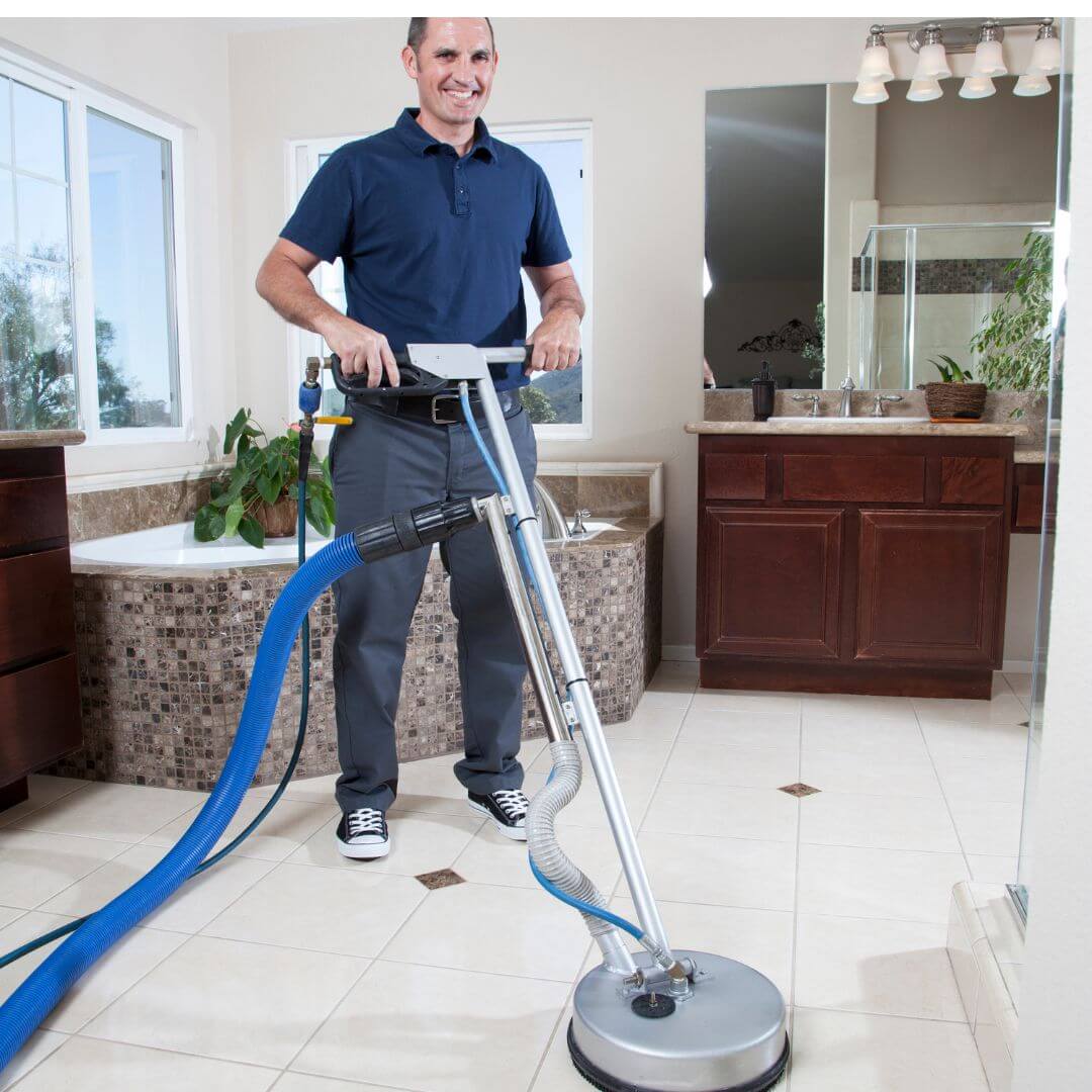 A man uses a vacuum cleaner to thoroughly clean a bathroom floor tile and Grout cleaning, ensuring a tidy and hygienic environment.